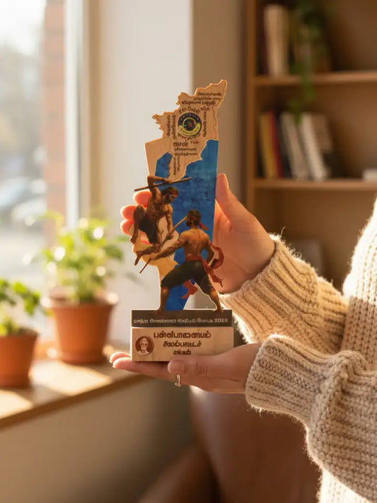 Hand holding a wooden map of a region with a person on it, in a home setting with plants and books.