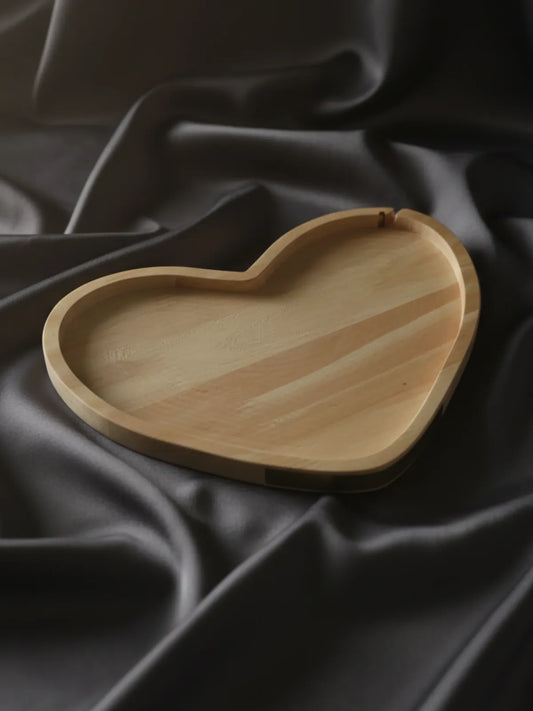 Heart-shaped wooden tray on a dark fabric background