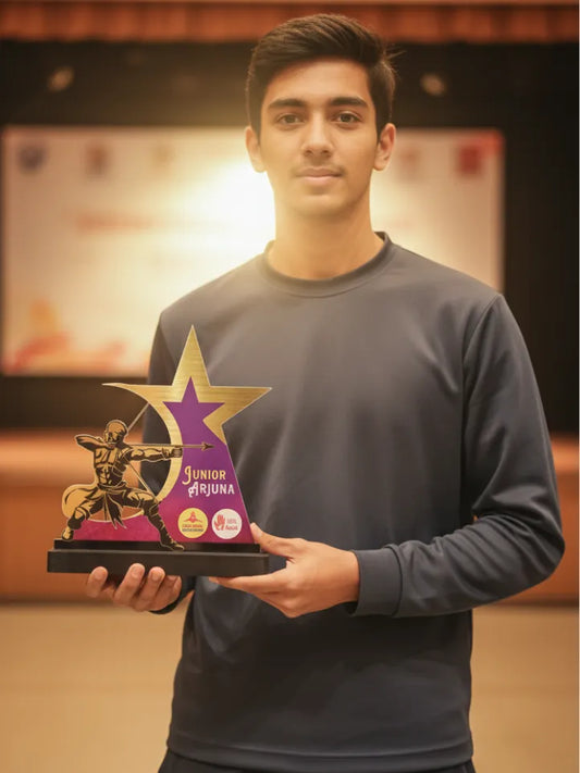 Person holding a trophy with a star design and 'Junior Arjuna' branding.