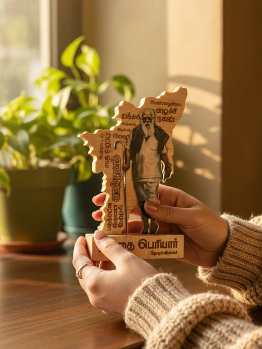 Person holding a wooden puzzle with text and images, with plants in the background