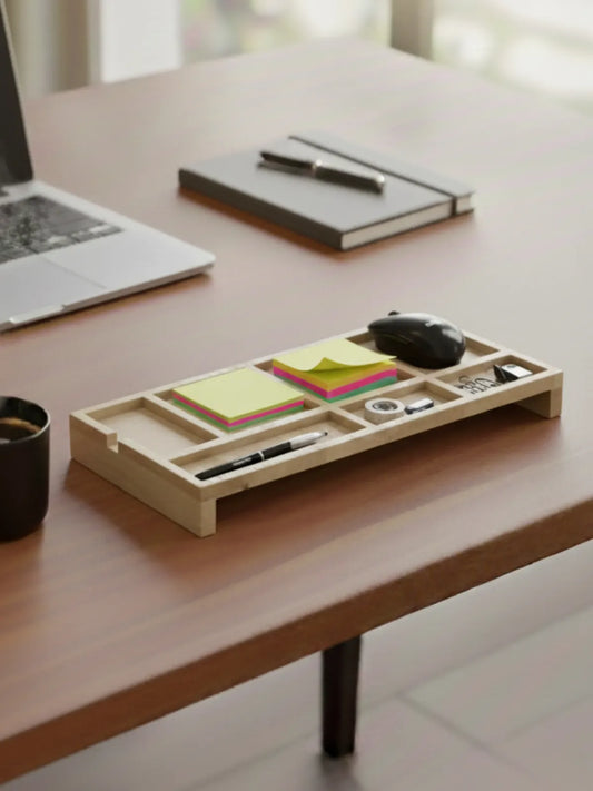 Office desk setup featuring wooden organizer tray with pens, clips, and supplies on natural wood surface