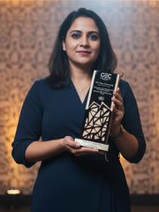 Woman holding an award with a geometric design against a warm-toned background