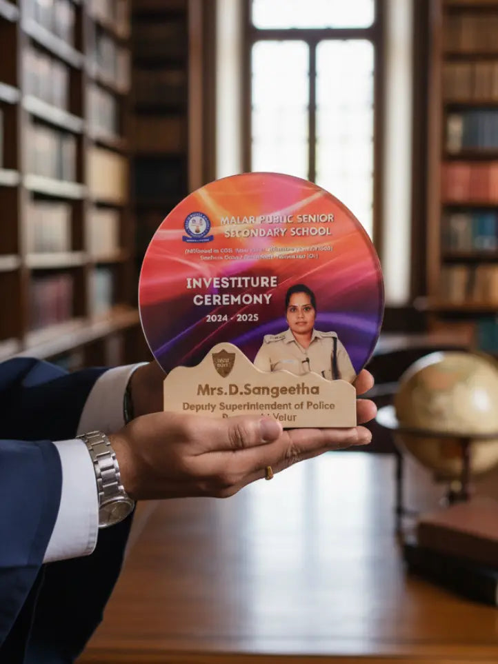 Person holding a circular plaque with 'Investiture Ceremony' details in a library setting