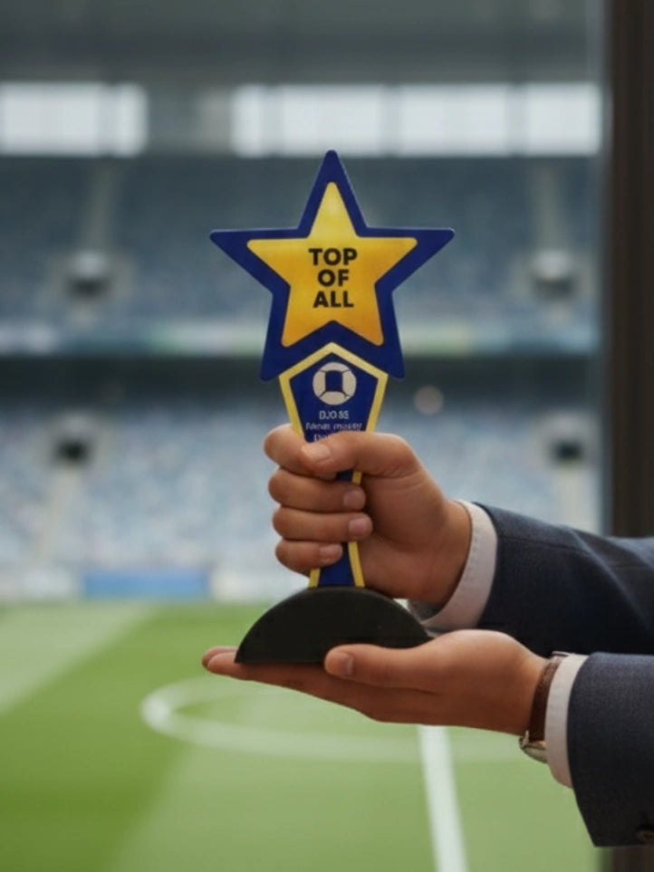 Hand holding a star-shaped trophy labeled 'Top of All' on a sports field.