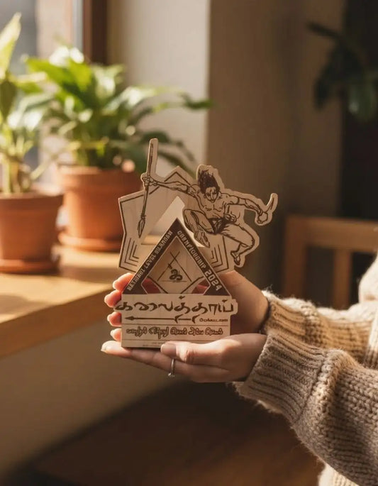 Person holding a deck of cards with pyramid design and illustrations, surrounded by plants indoors.