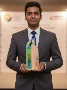 Man in a suit holding an award with '2021' on it, standing in front of a blurred background.