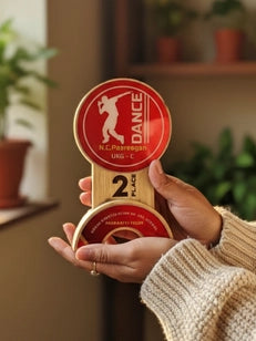 Hand holding a red and beige dance foam finger with a logo and text.