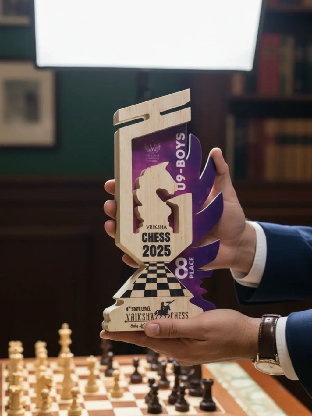 Person holding a chess-themed trophy with 'Vishwaroop Chess 2025' branding in a room with a chessboard.