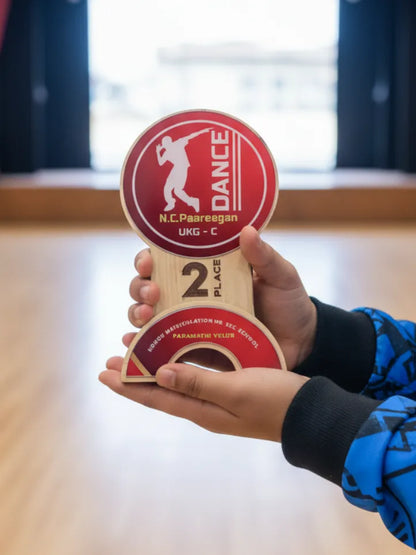 Hand holding a red and wooden dance award with 'N.C. Paareegan' branding.