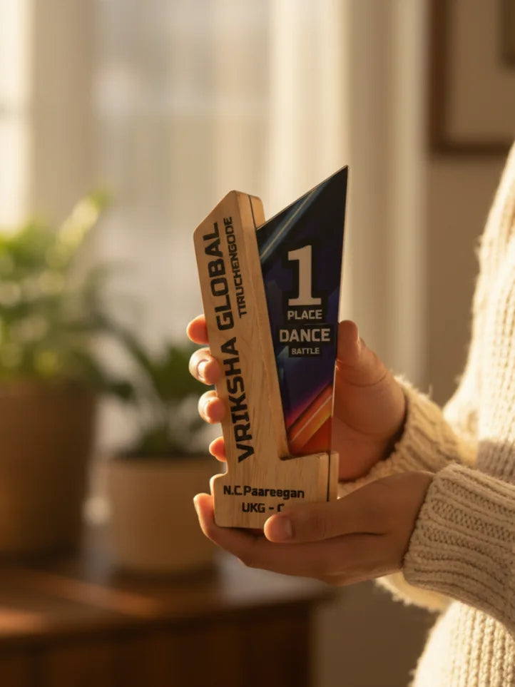 Hand holding a wooden trophy with 'Vriksha Global' branding indoors.