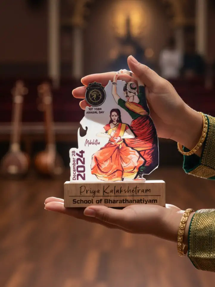 Hand holding a decorative card with a dancer design and text, set against a blurred background.