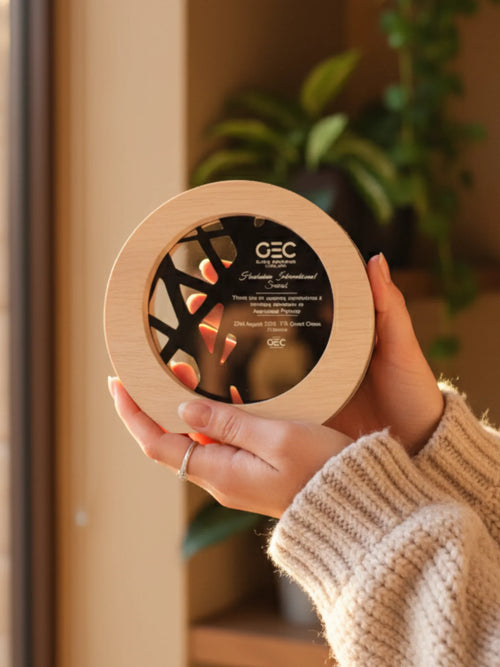 Person holding a circular wooden product with 'GEC' branding in a home setting.