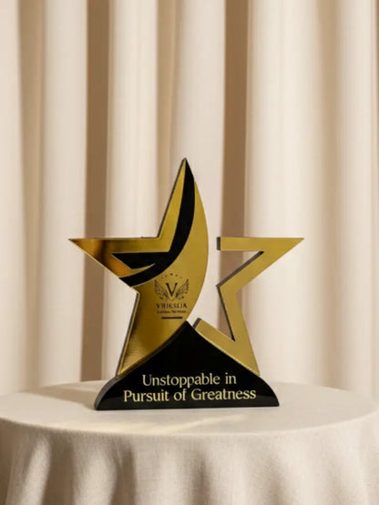Gold and black star-shaped award on a white surface with a beige curtain background