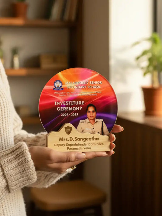 Person holding a circular award with text and a photo of a woman, set against a blurred indoor background.