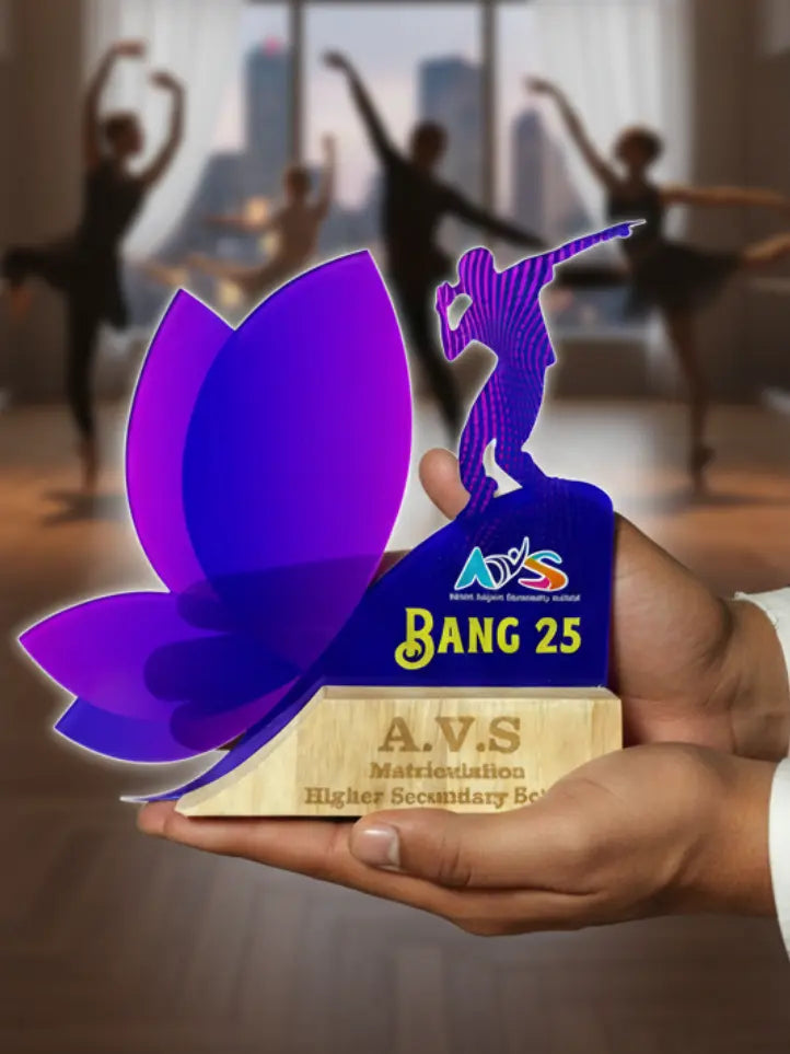 A hand holding a decorative award with 'A.V.S' branding in a dance studio setting.