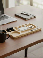 Desk setup with a wooden tray holding office supplies, a laptop, and a coffee cup.