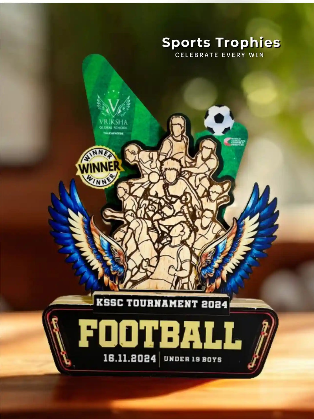 Sports trophy for KSSC Tournament 2024 Football with wings and text on a wooden surface.