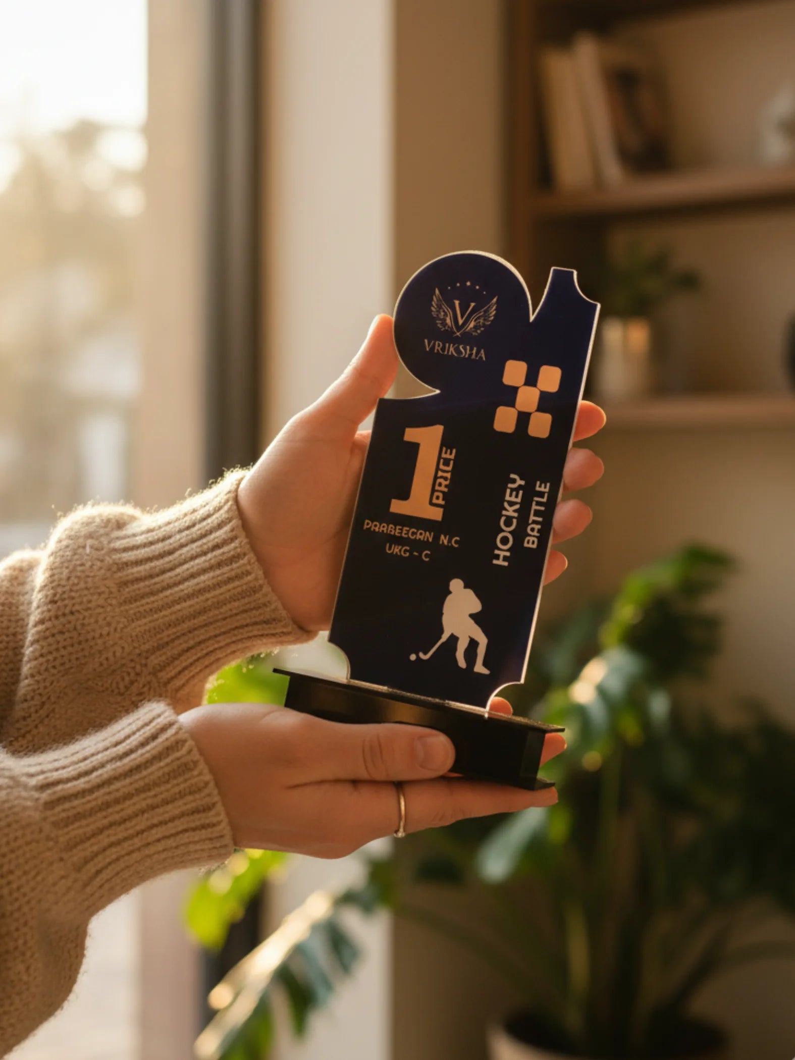 Hand holding a hockey trophy with 'Vesmania' branding indoors.