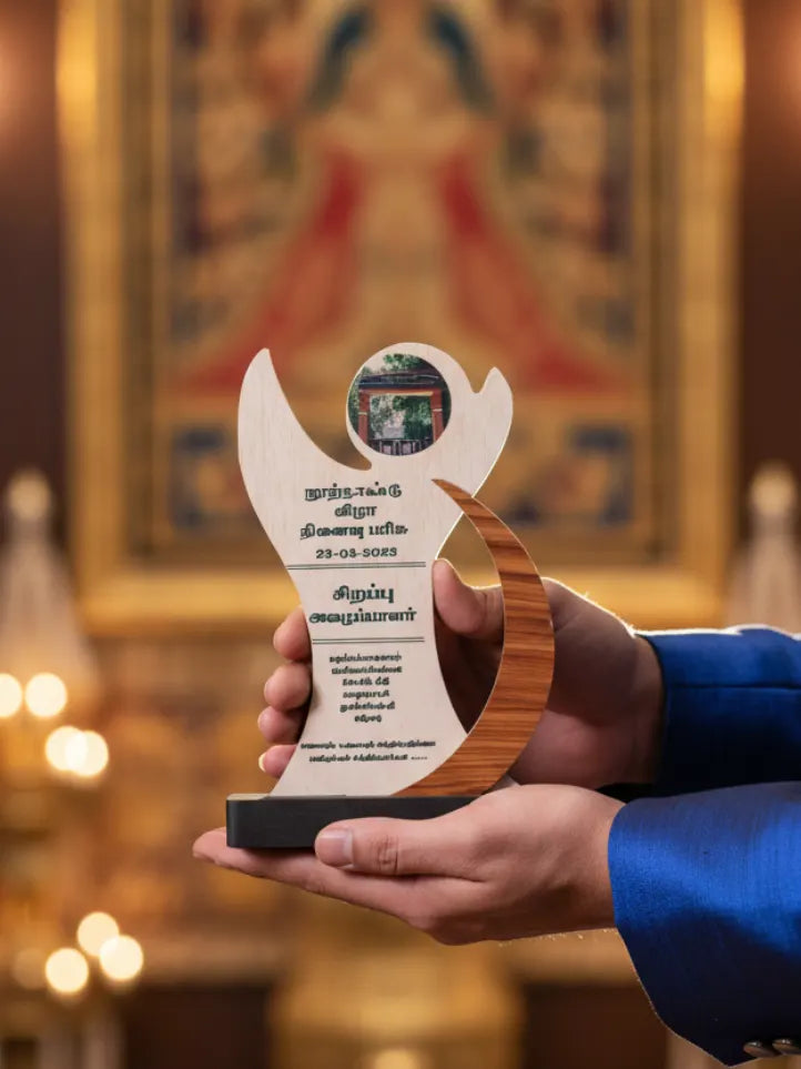 Hand holding a wooden award with text against a blurred background