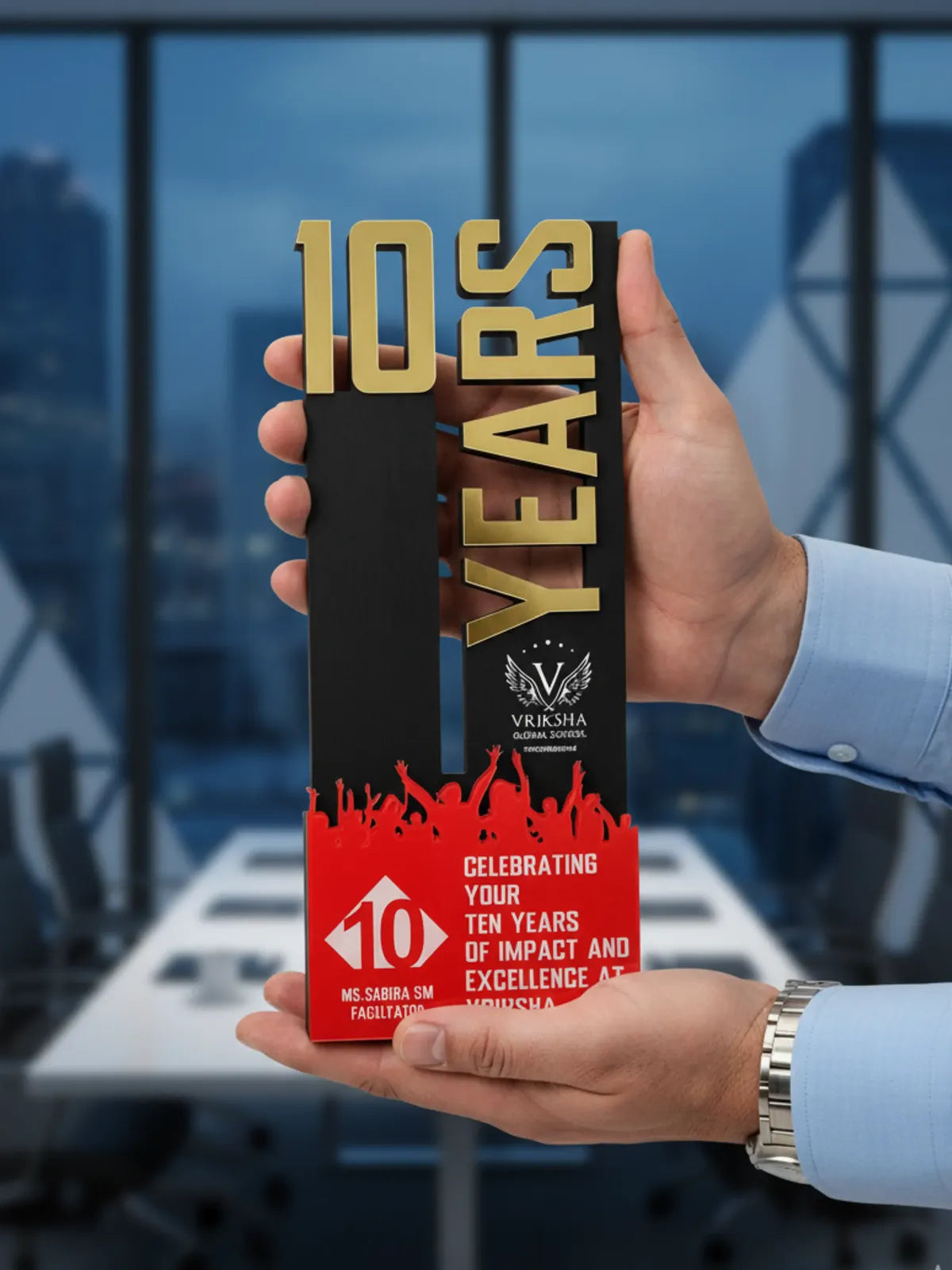 Hand holding a '10 Years' award with red and gold design against a blurred office background