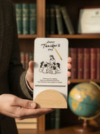 Person holding a card with a teacher's day message in front of a bookshelf.