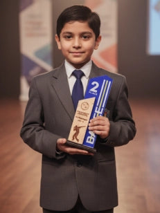 Young boy in a suit holding an award with a blue ribbon