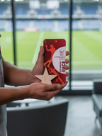 Person holding a red phone case with a star design in front of a blurred indoor background