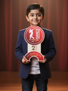 Child holding a red award with a logo and text against a curtain background