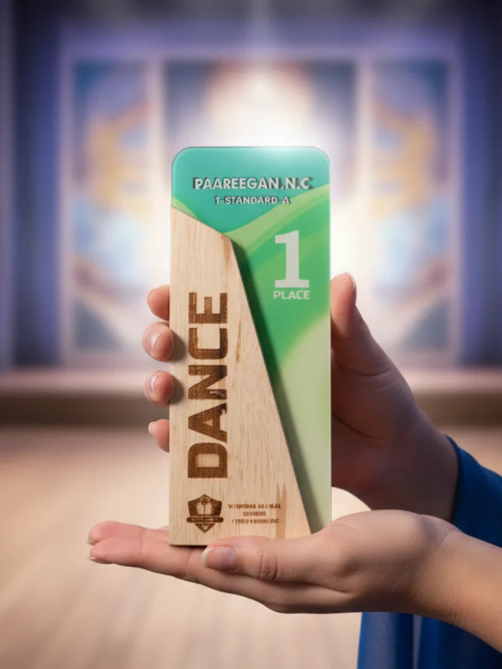 Hand holding a wooden award with 'DANCE' engraved on it against a blurred indoor background
