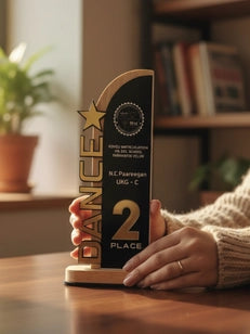 Person holding a trophy with 'DanceX' branding on a wooden surface.