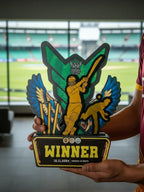 Person holding a colorful trophy with 'Winner' text in front of a sports stadium.