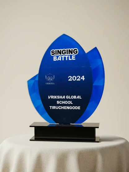 Blue trophy with 'Singing Battle 2024' and 'Vriksha Global School Tiruchengode' text on a beige background