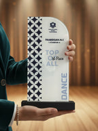 Person holding a dance award with 'Top of All' text against a blurred background