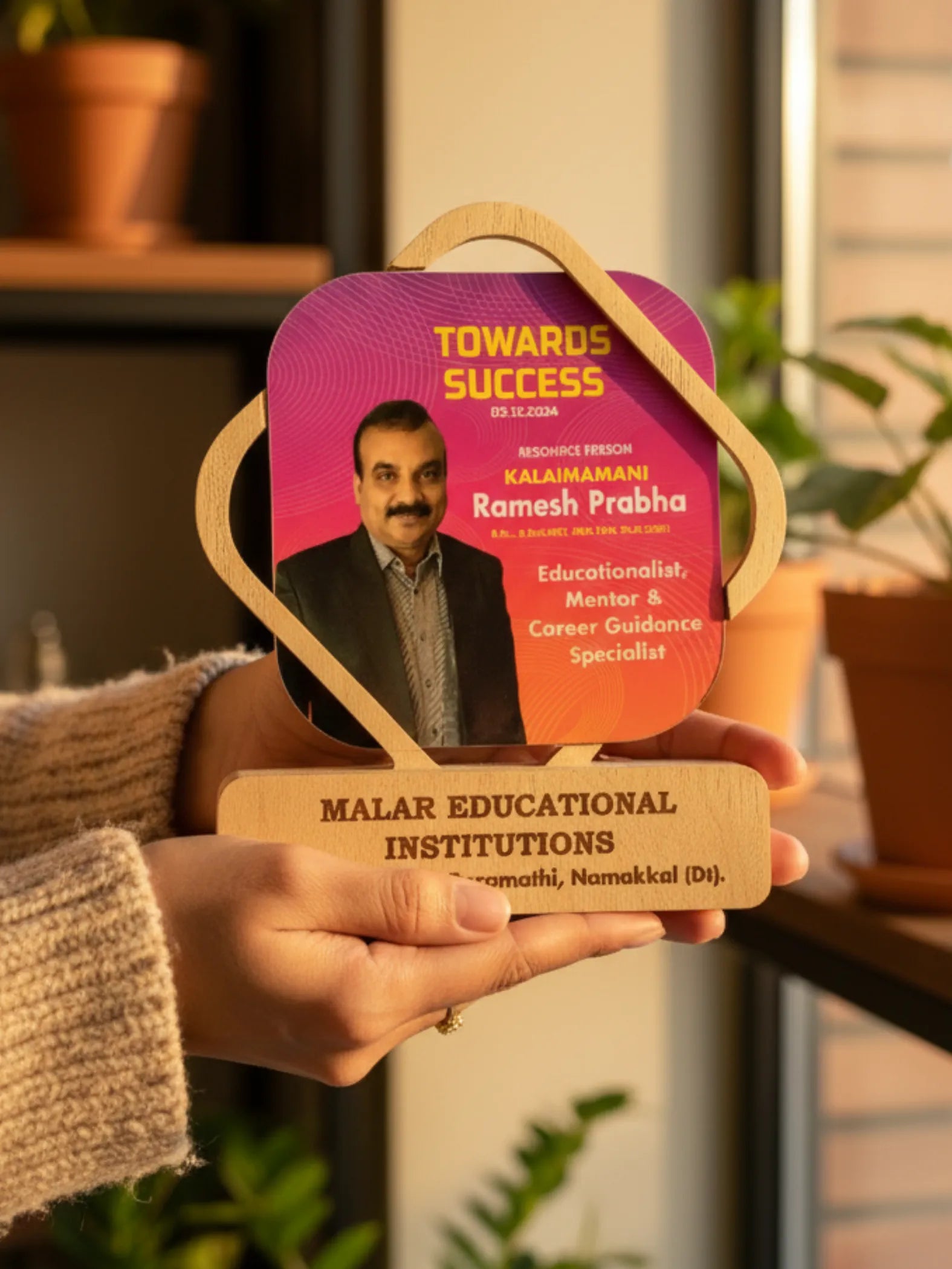 Person holding a decorative award with a purple and orange design featuring a portrait and text.