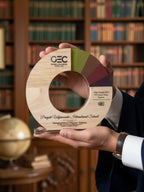 Person holding a wooden award with GEC branding in a library setting