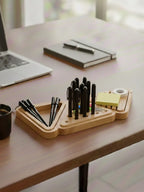 Wooden desk organizer with pens and a notebook on a desk.
