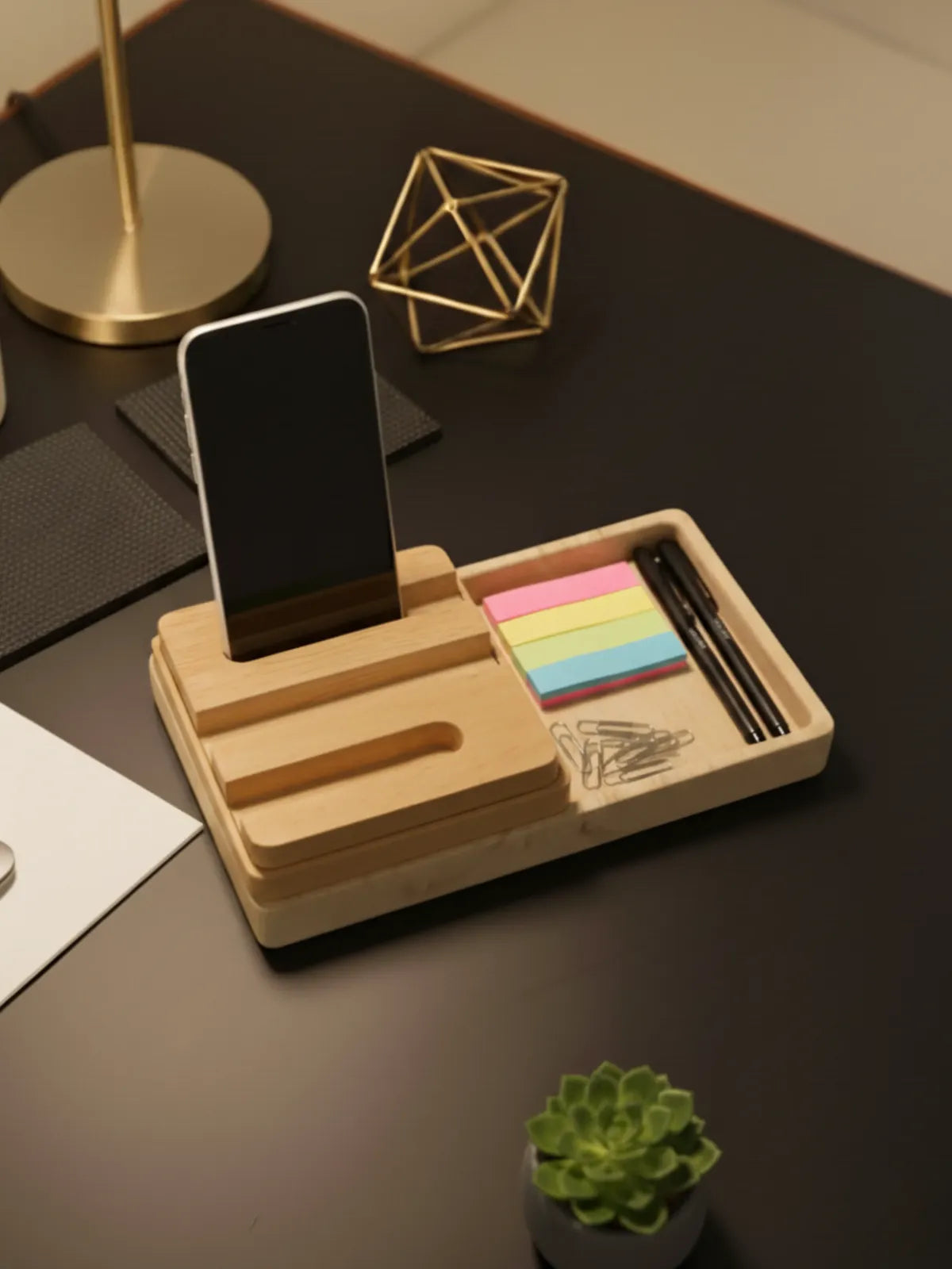 Wooden desk organizer with phone stand, sticky notes, and pens on a dark surface.