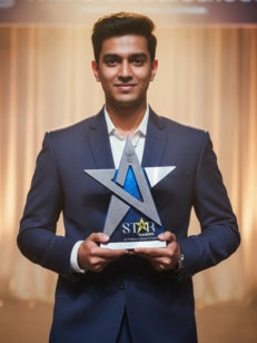 Man in a blue suit holding an award with a star design against a blurred background