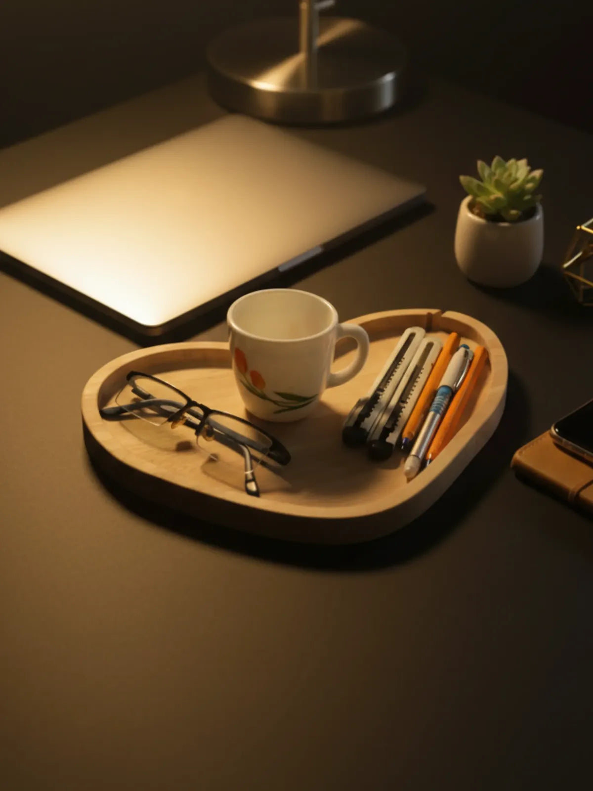 Wooden tray with a mug, glasses, and stationery on a dark surface.