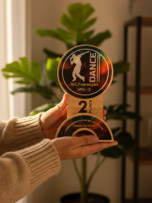 Hand holding a dance competition trophy with 'N.C. Paareegan' branding
