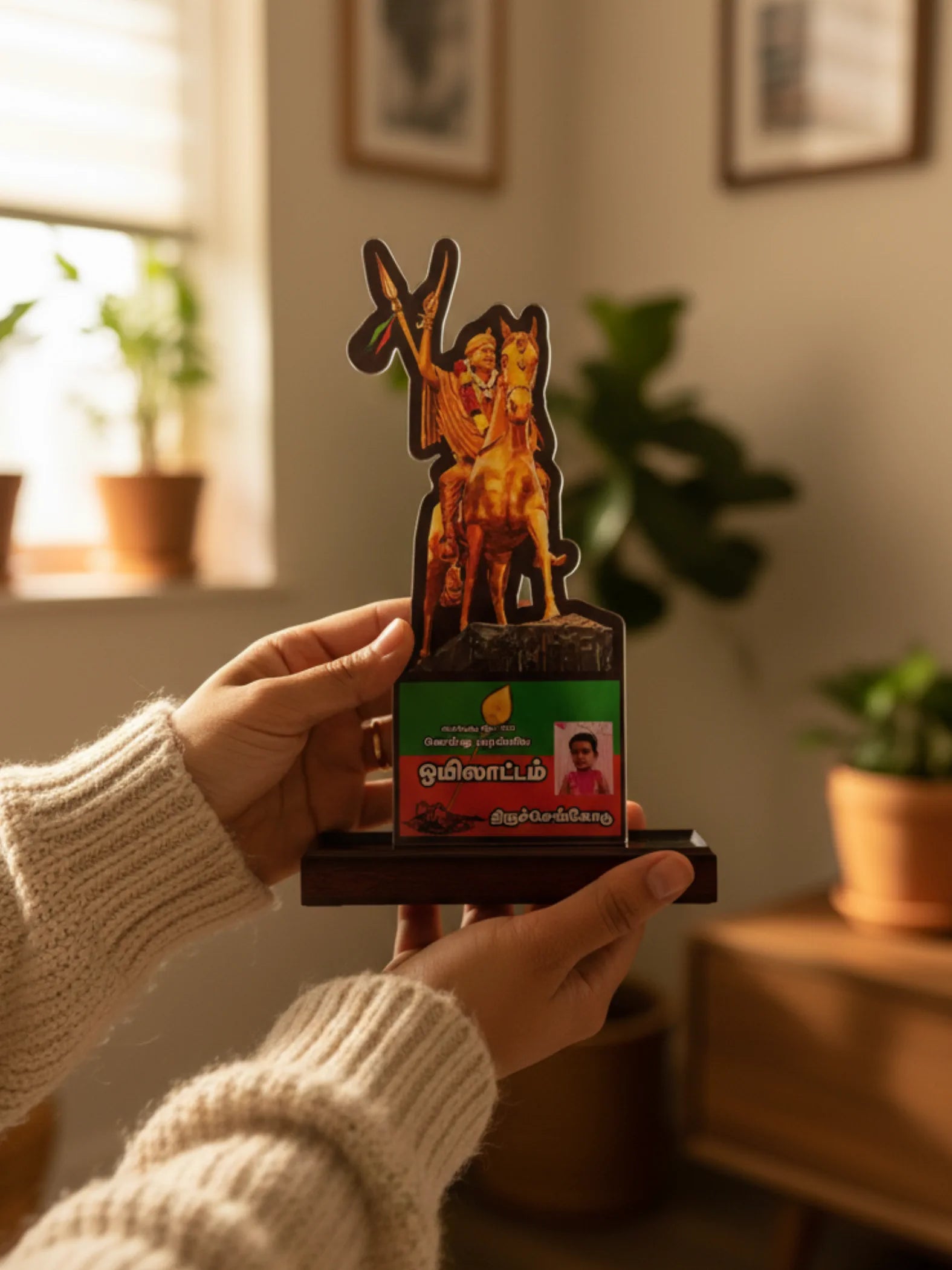 Person holding a decorative item with a horse and rider design in a home setting