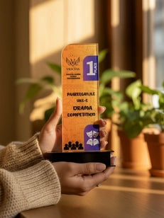 Person holding an award with a blue and gold design, indoors with plants in the background