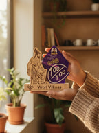 Hand holding a wooden product with 'Vetri Vikaas' branding in a home setting.