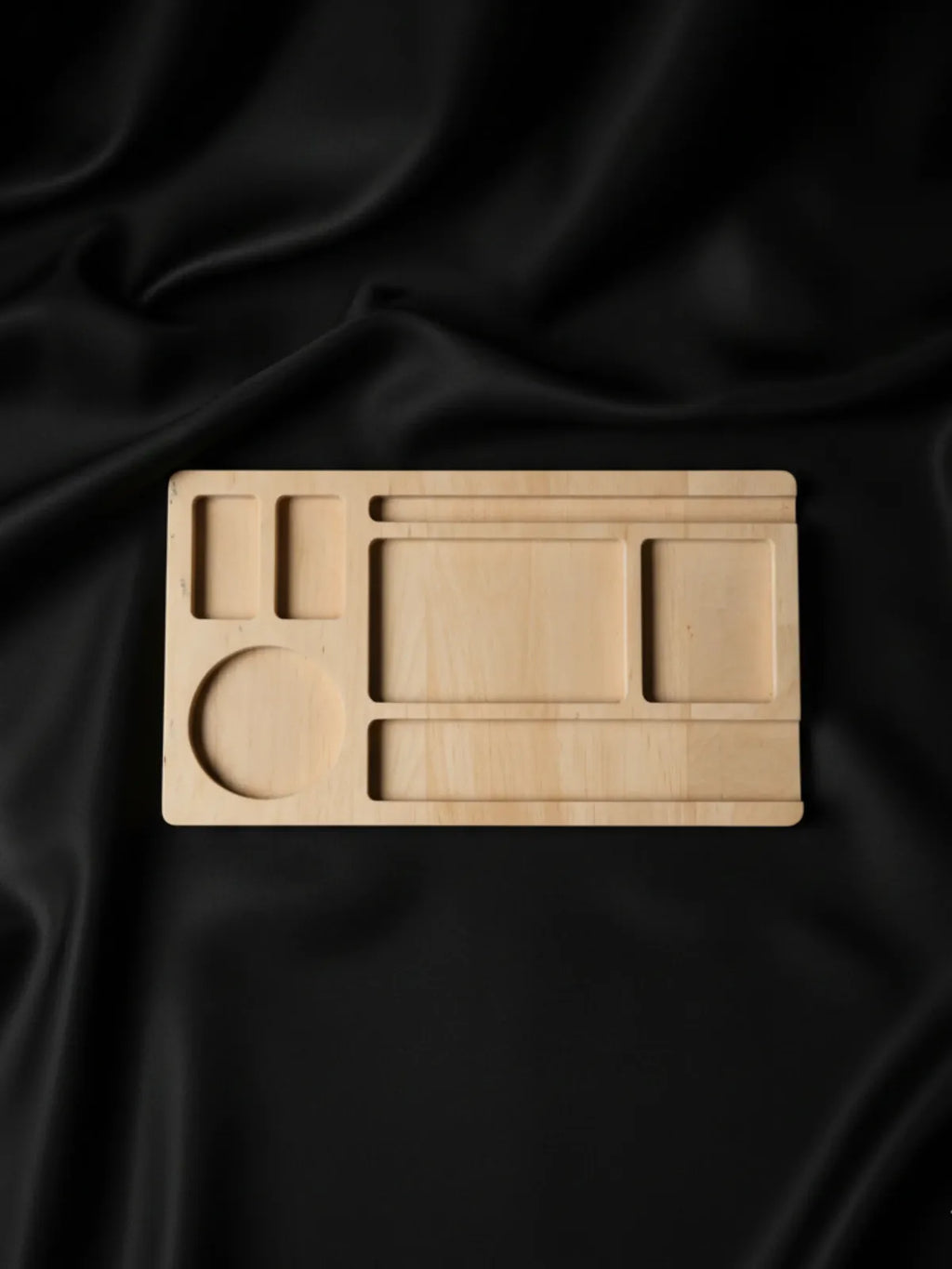 Wooden tray with geometric compartments on a black satin background