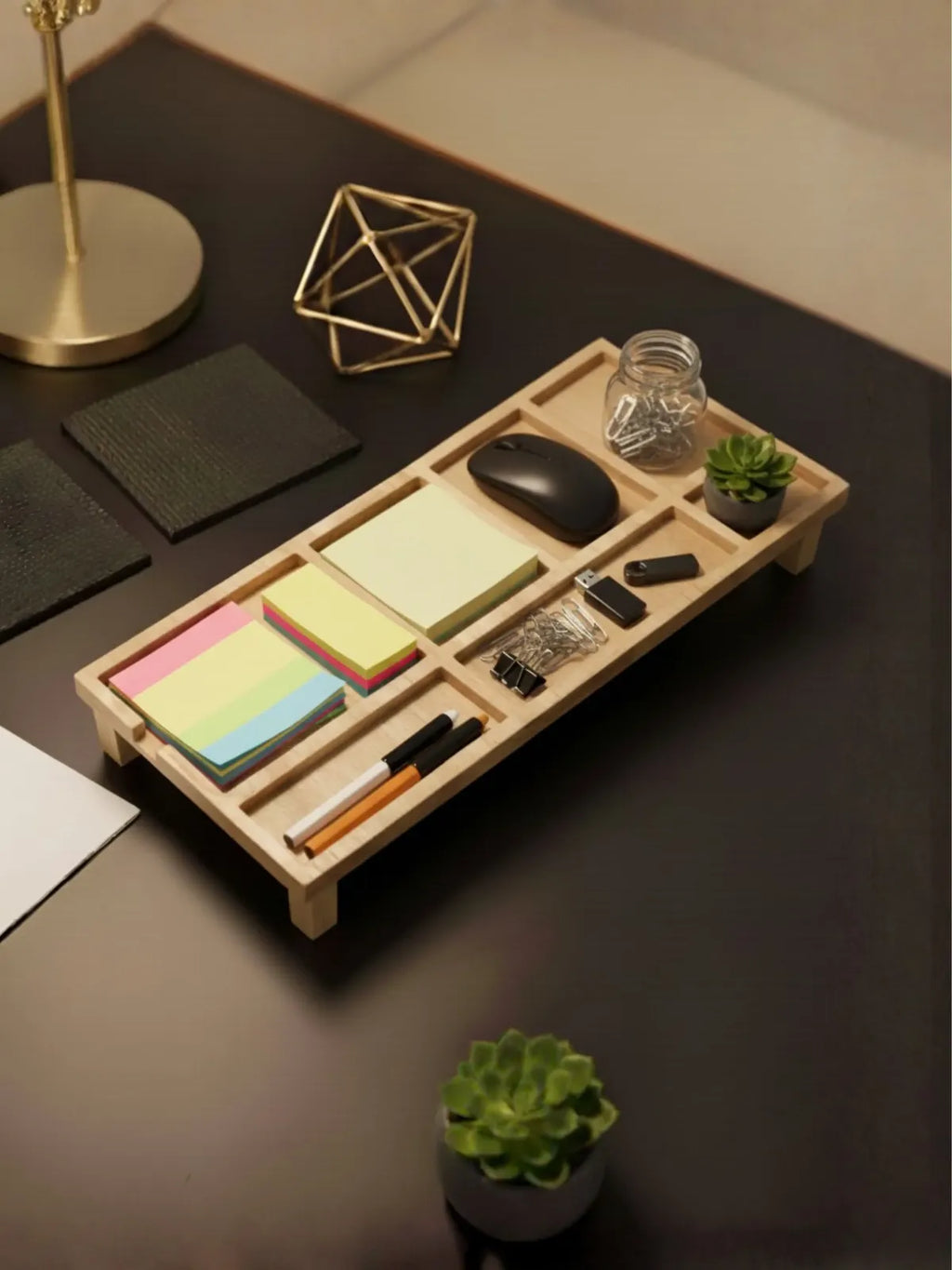Wooden desk organizer tray with stationery items including pens and office supplies on dark surface