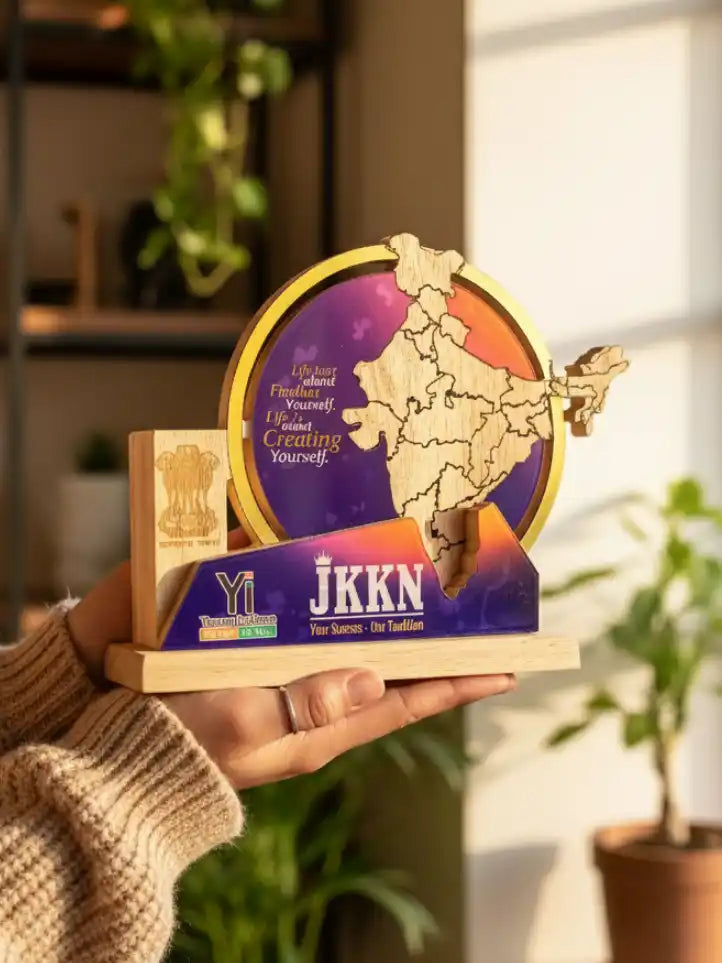 Hand holding a wooden map model with colorful design and text, set against a blurred indoor background.