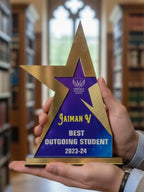 Person holding a star-shaped award with 'Best Outgoing Student 2023-24' text in a library setting