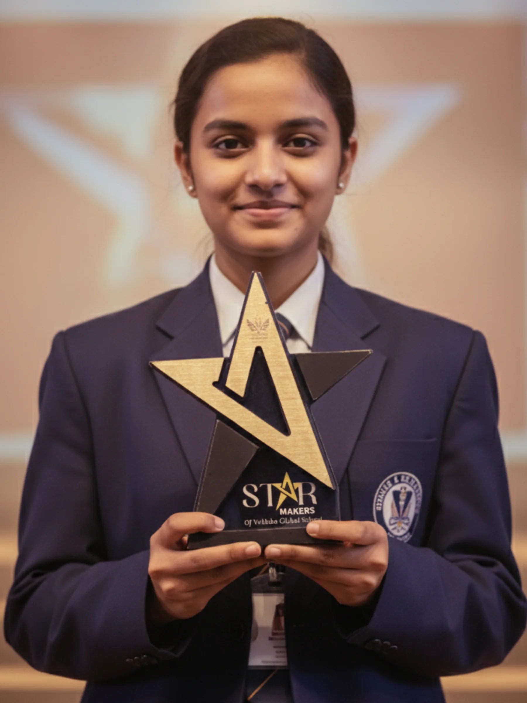 Person in a formal outfit holding a star-shaped award with 'STAR MAKERS' on a blurred background