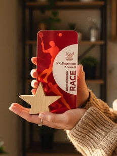 Hand holding a red and white award with a star on a blurred indoor background