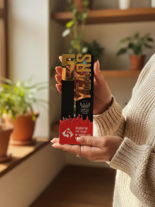 Person holding a 15th anniversary trophy with plants in the background